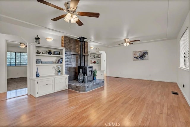 unfurnished living room featuring plenty of natural light, light hardwood / wood-style floors, and a wood stove