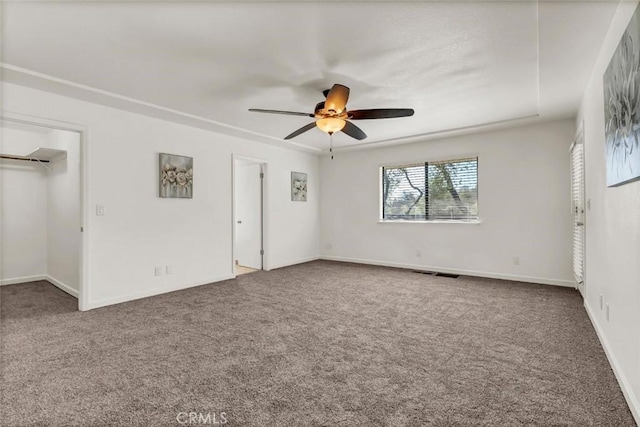 unfurnished bedroom featuring a spacious closet, carpet floors, and ceiling fan