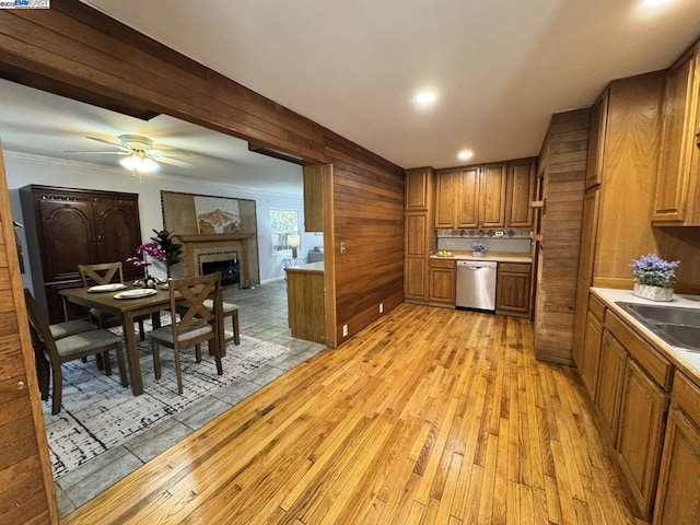 kitchen featuring sink, wooden walls, dishwasher, and light wood-type flooring