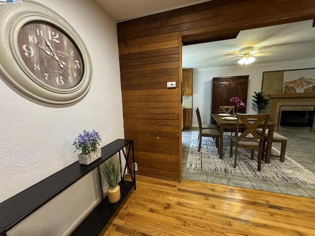 dining room with crown molding, ceiling fan, wood-type flooring, and wood walls