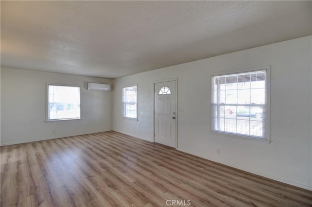 foyer entrance featuring a wall unit AC and light hardwood / wood-style flooring