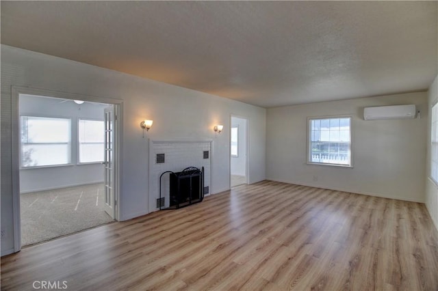 unfurnished living room with a fireplace, light hardwood / wood-style flooring, and an AC wall unit