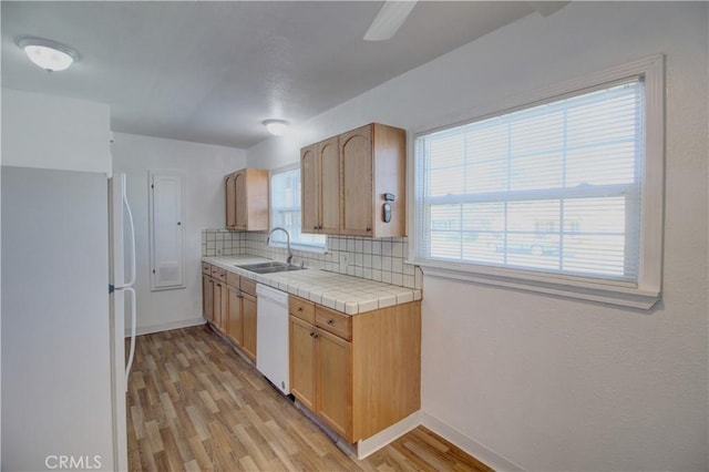 kitchen featuring sink, light hardwood / wood-style flooring, tile counters, white appliances, and decorative backsplash