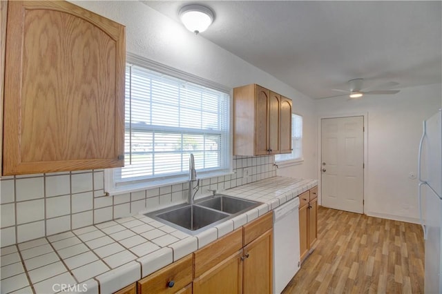 kitchen featuring tile countertops, tasteful backsplash, sink, light wood-type flooring, and white appliances