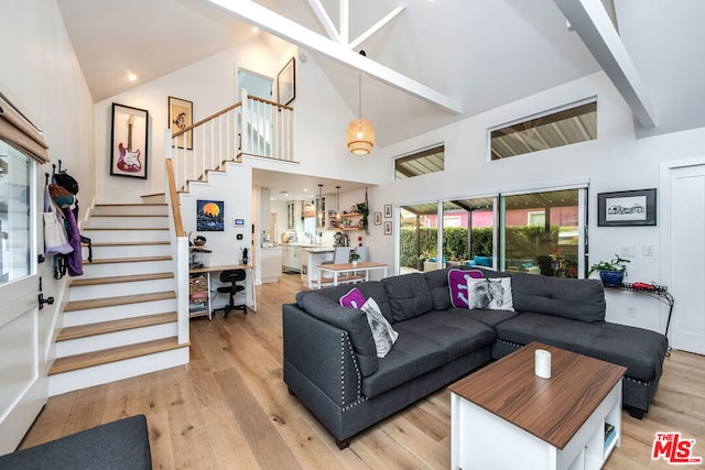 living room with high vaulted ceiling, light hardwood / wood-style floors, and beamed ceiling