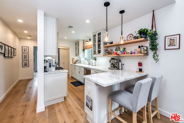 kitchen featuring backsplash, white cabinets, a kitchen breakfast bar, hanging light fixtures, and kitchen peninsula