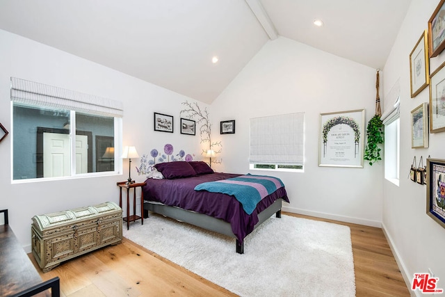 bedroom with high vaulted ceiling, beam ceiling, and light hardwood / wood-style floors