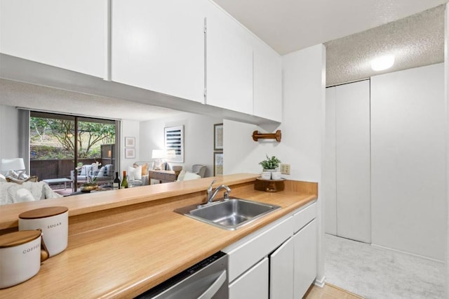 kitchen featuring white cabinetry, stainless steel dishwasher, sink, and a textured ceiling