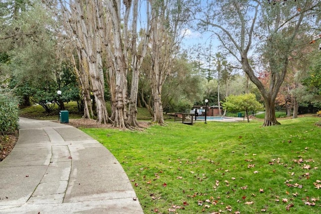 view of home's community with a pool and a yard