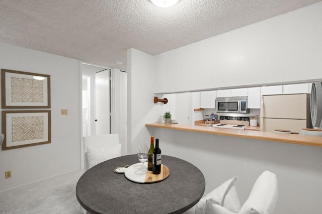 dining area with light colored carpet and a textured ceiling