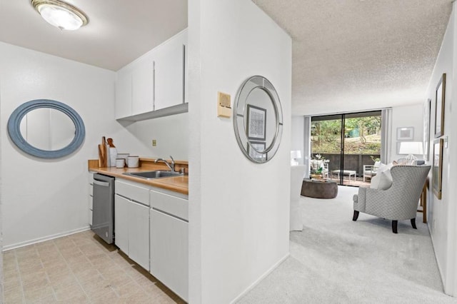 kitchen with sink, light carpet, a textured ceiling, dishwasher, and white cabinets