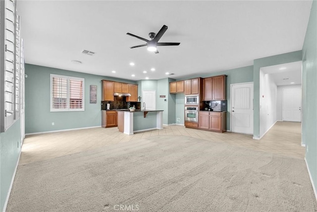 kitchen with appliances with stainless steel finishes, decorative backsplash, ceiling fan, sink, and light colored carpet