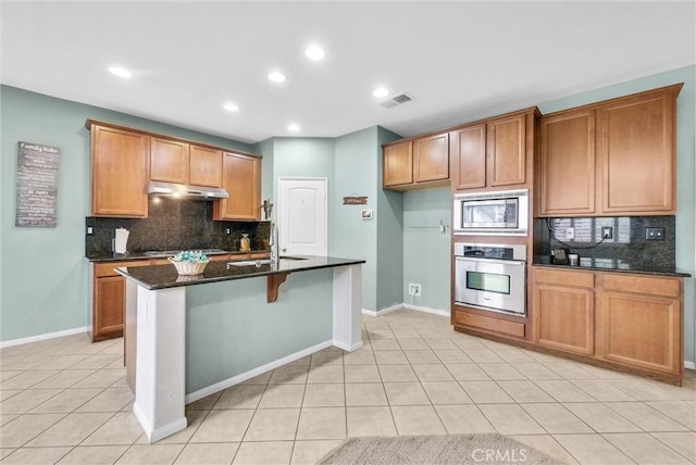 kitchen featuring stainless steel appliances, visible vents, light tile patterned flooring, a sink, and under cabinet range hood