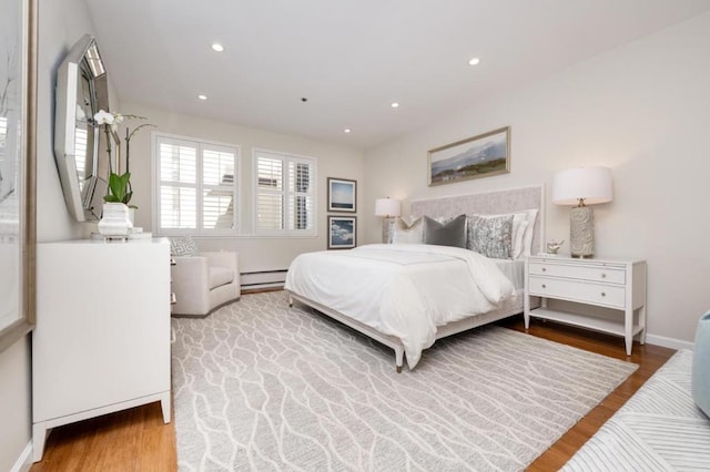 bedroom featuring a baseboard heating unit and wood-type flooring