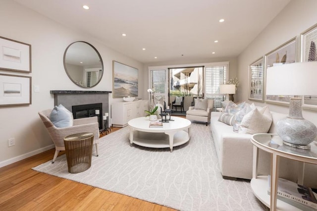 living room with a tiled fireplace and light hardwood / wood-style flooring