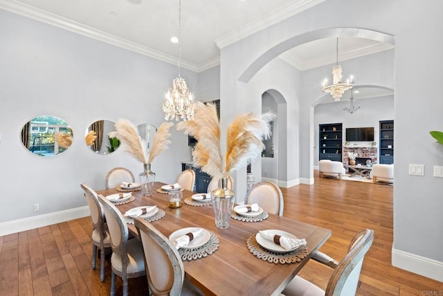 dining room featuring an inviting chandelier, ornamental molding, built in shelves, and hardwood / wood-style floors