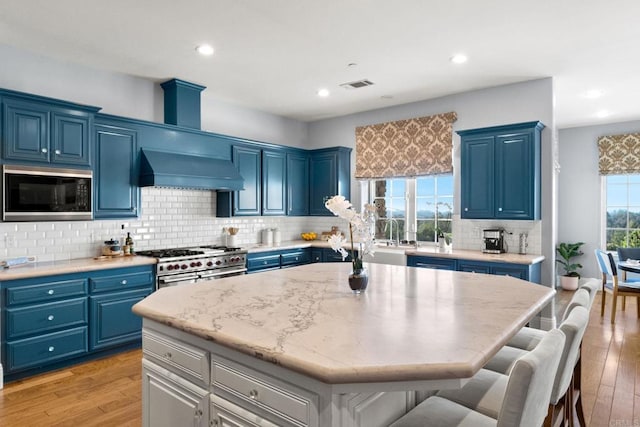 kitchen featuring premium range hood, blue cabinets, black microwave, range with two ovens, and a center island