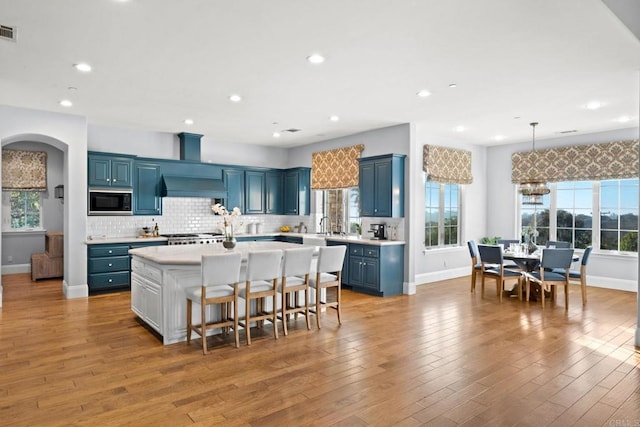 kitchen with backsplash, a kitchen island, black microwave, blue cabinets, and custom exhaust hood