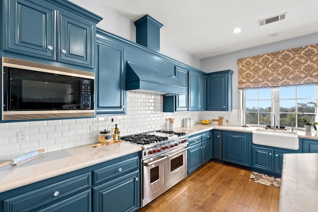 kitchen featuring range with two ovens, blue cabinets, sink, and black microwave