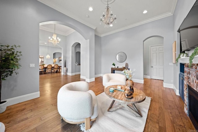 sitting room with crown molding, light wood-type flooring, and an inviting chandelier