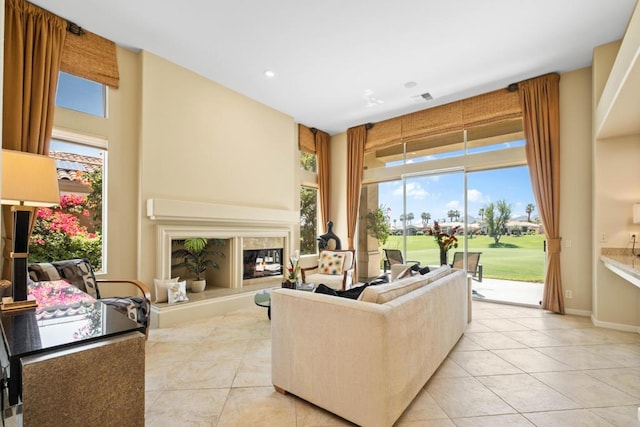 living room featuring a towering ceiling, light tile patterned floors, and a fireplace