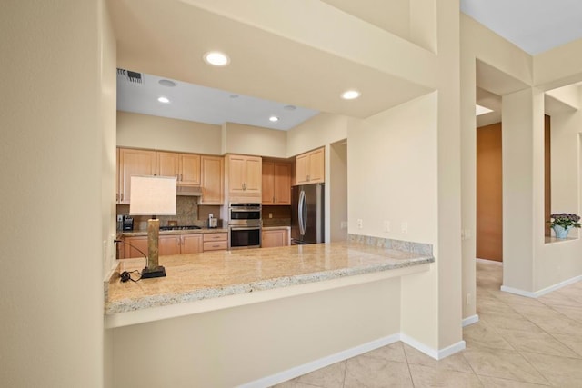 kitchen featuring light tile patterned floors, stainless steel appliances, light stone countertops, light brown cabinetry, and kitchen peninsula