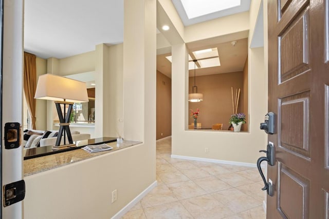 foyer with light tile patterned flooring and a skylight