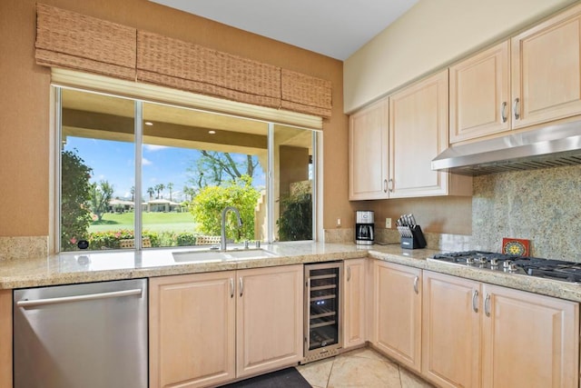 kitchen with light tile patterned flooring, sink, light stone counters, stainless steel appliances, and beverage cooler