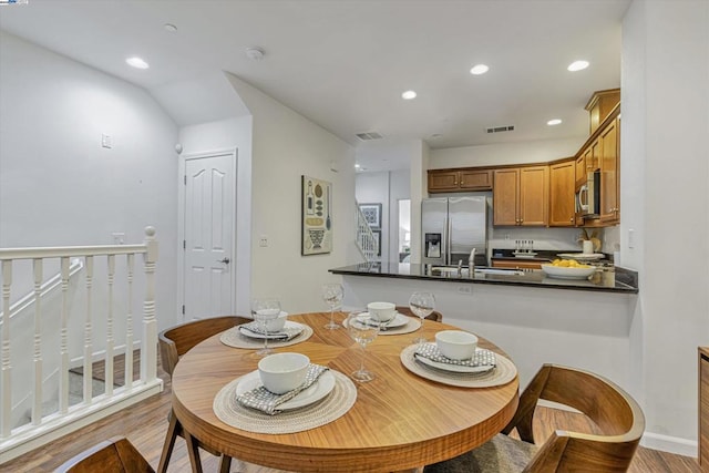 kitchen featuring sink, light hardwood / wood-style floors, kitchen peninsula, and appliances with stainless steel finishes