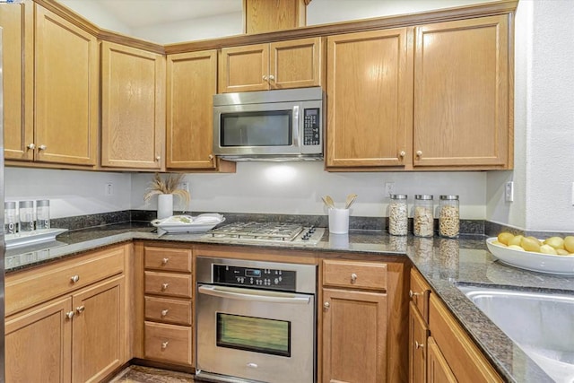 kitchen featuring appliances with stainless steel finishes, sink, and dark stone counters