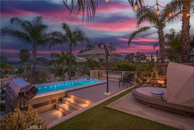 pool at dusk with a deck with mountain view