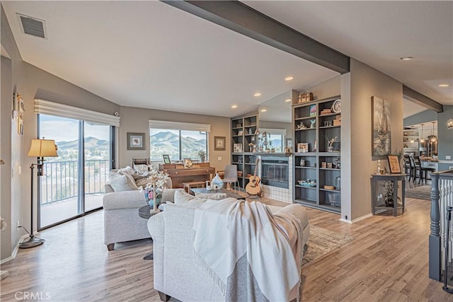 living room featuring lofted ceiling with beams and light hardwood / wood-style flooring