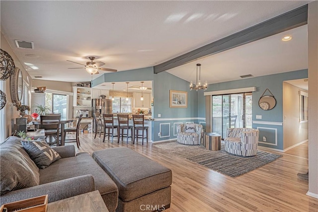 living room featuring vaulted ceiling with beams, light hardwood / wood-style flooring, and a healthy amount of sunlight