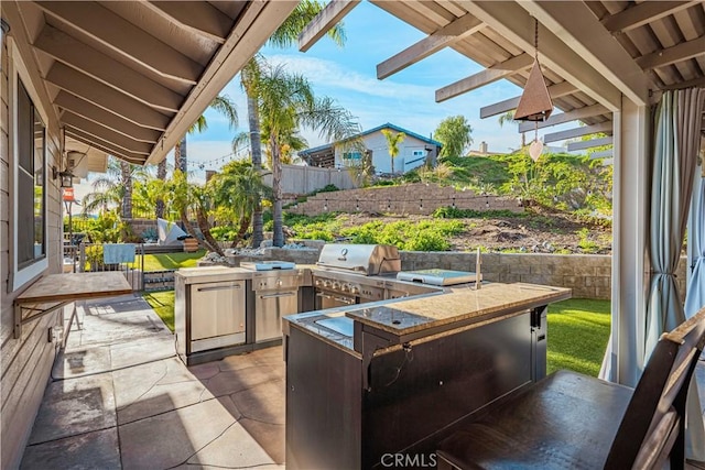 view of patio with exterior kitchen and a grill