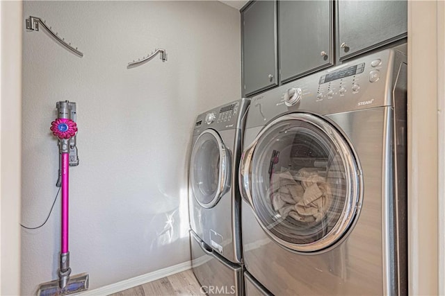 clothes washing area with cabinets, a mail area, washer and clothes dryer, and light hardwood / wood-style floors