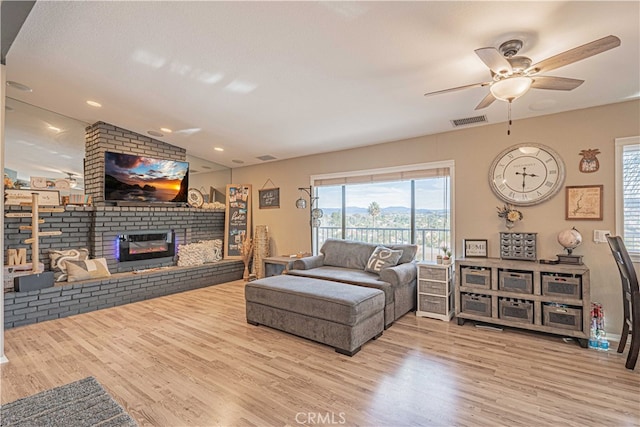 living room featuring lofted ceiling, a brick fireplace, light hardwood / wood-style flooring, and ceiling fan