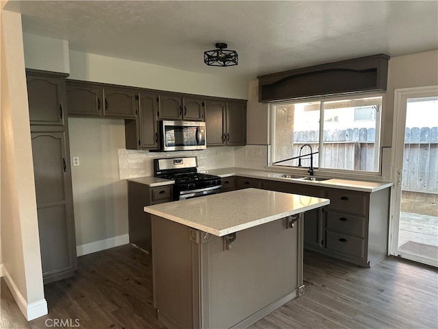 kitchen with dark hardwood / wood-style flooring, sink, a kitchen island, and appliances with stainless steel finishes