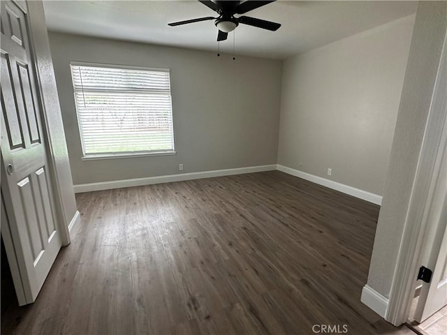 empty room with ceiling fan and dark hardwood / wood-style flooring