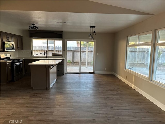 kitchen featuring dark hardwood / wood-style floors, sink, hanging light fixtures, a center island, and stainless steel appliances