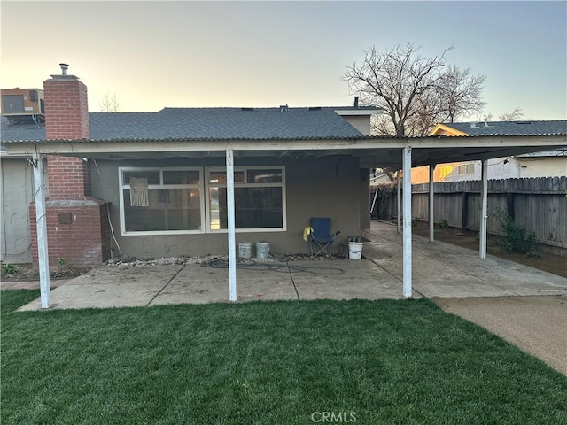 back house at dusk featuring a lawn, central air condition unit, and a patio area