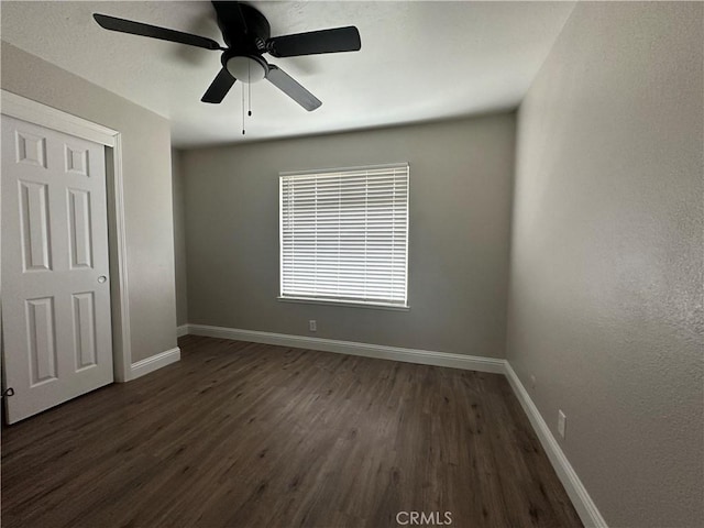 unfurnished bedroom with dark wood-type flooring, ceiling fan, and a closet