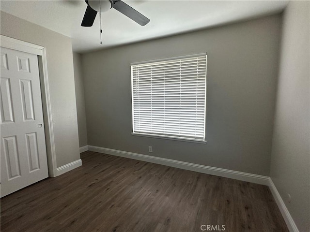 unfurnished bedroom featuring dark hardwood / wood-style floors, ceiling fan, and a closet