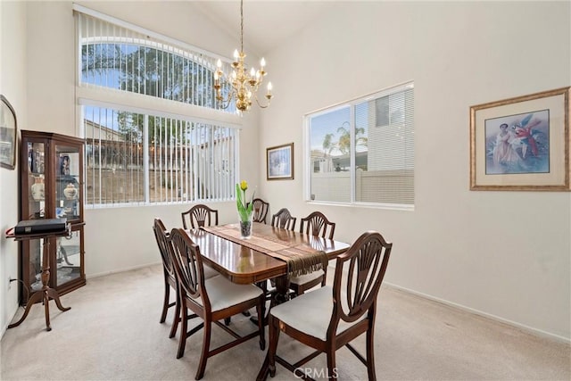 dining space with baseboards, light carpet, a notable chandelier, and a high ceiling