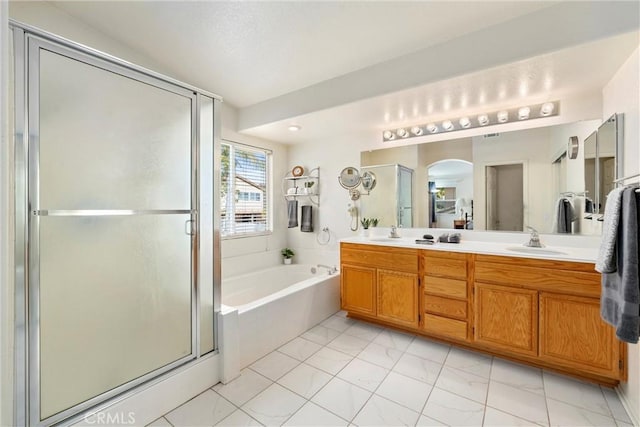 bathroom featuring a sink, double vanity, a shower stall, and a garden tub