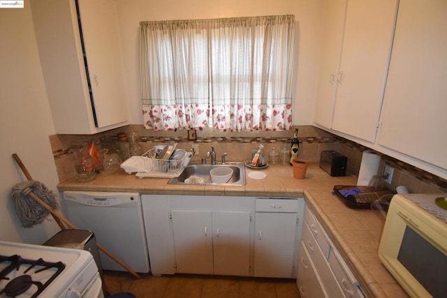 kitchen with tile countertops, tasteful backsplash, white cabinetry, sink, and white appliances