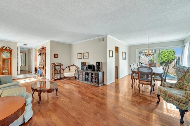 living room featuring a notable chandelier, ornamental molding, light hardwood / wood-style floors, and a textured ceiling