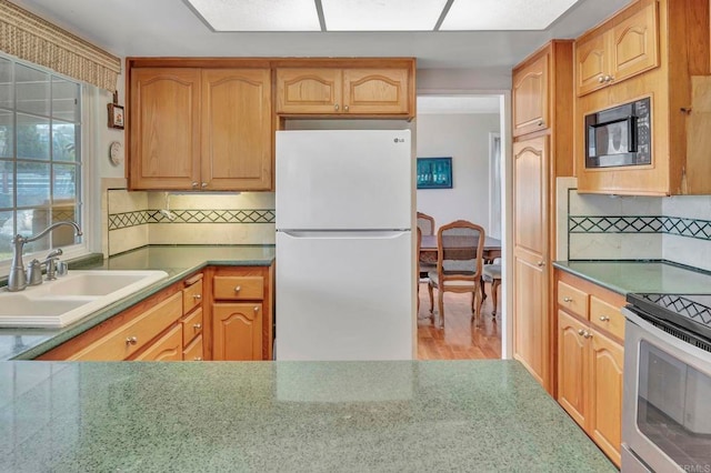 kitchen with sink, black microwave, white refrigerator, decorative backsplash, and stainless steel electric stove