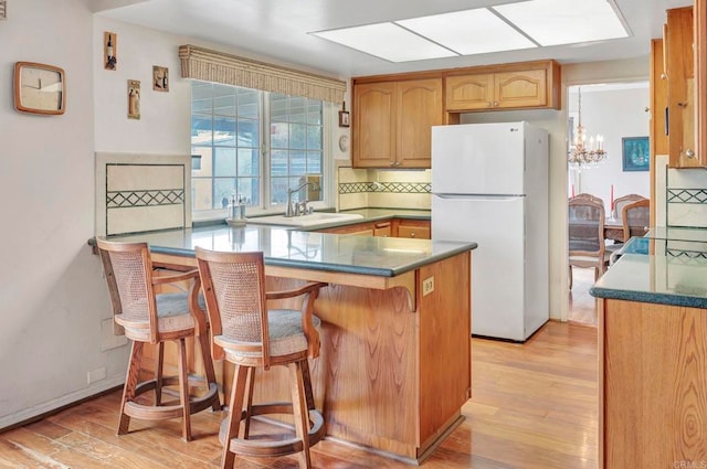 kitchen with a kitchen bar, kitchen peninsula, sink, and white fridge