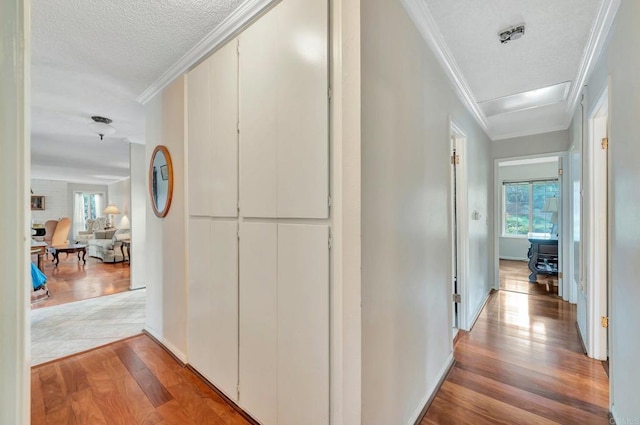 hall featuring ornamental molding, a textured ceiling, and light hardwood / wood-style flooring