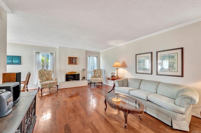 living room with crown molding, a brick fireplace, a textured ceiling, and light hardwood / wood-style floors